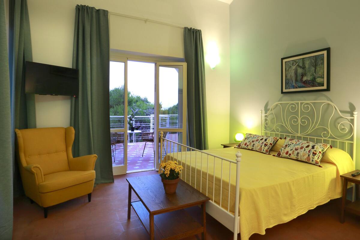 Une chambre à coucher comprenant un lit, une chaise, une table et un balcon avec une balustrade.