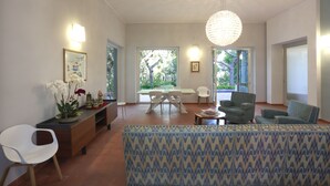A spacious living area with a dining table, chairs, a sofa, and a decorative chandelier. - Dimora Villa Serena Porto Selvaggio (Nardò)
