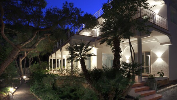A modern house with a covered outdoor area, a staircase, and a pathway surrounded by greenery. - Dimora Villa Serena Porto Selvaggio (Nardò)