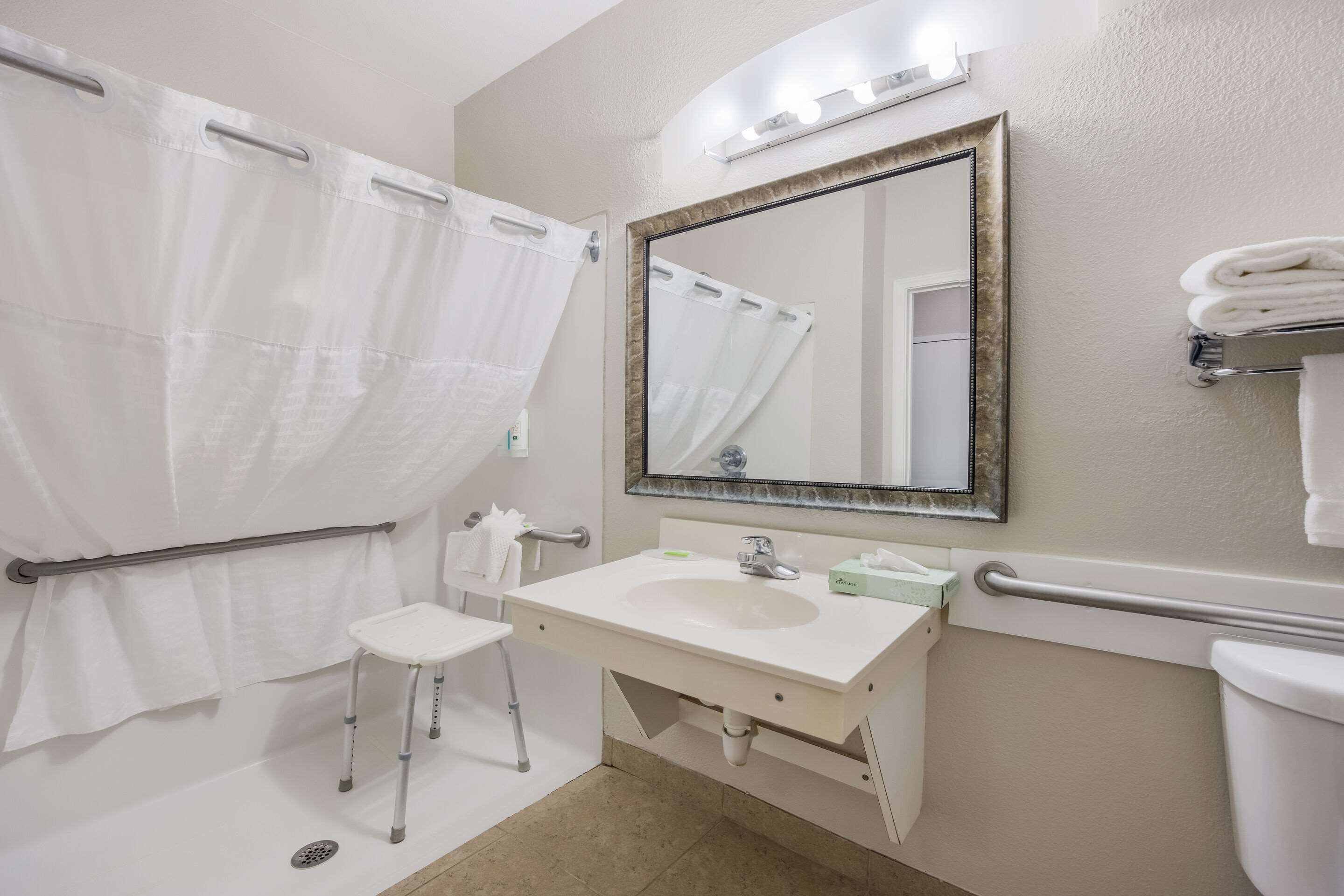 A bathroom with a white sink, a mirror, a shower curtain, and a toilet.