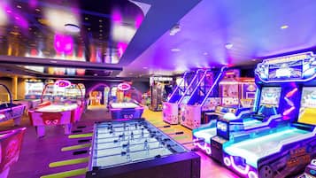 Un salón de juegos recreativos con varias máquinas, incluyendo mesas de fútbol de mesa y juegos de carreras.