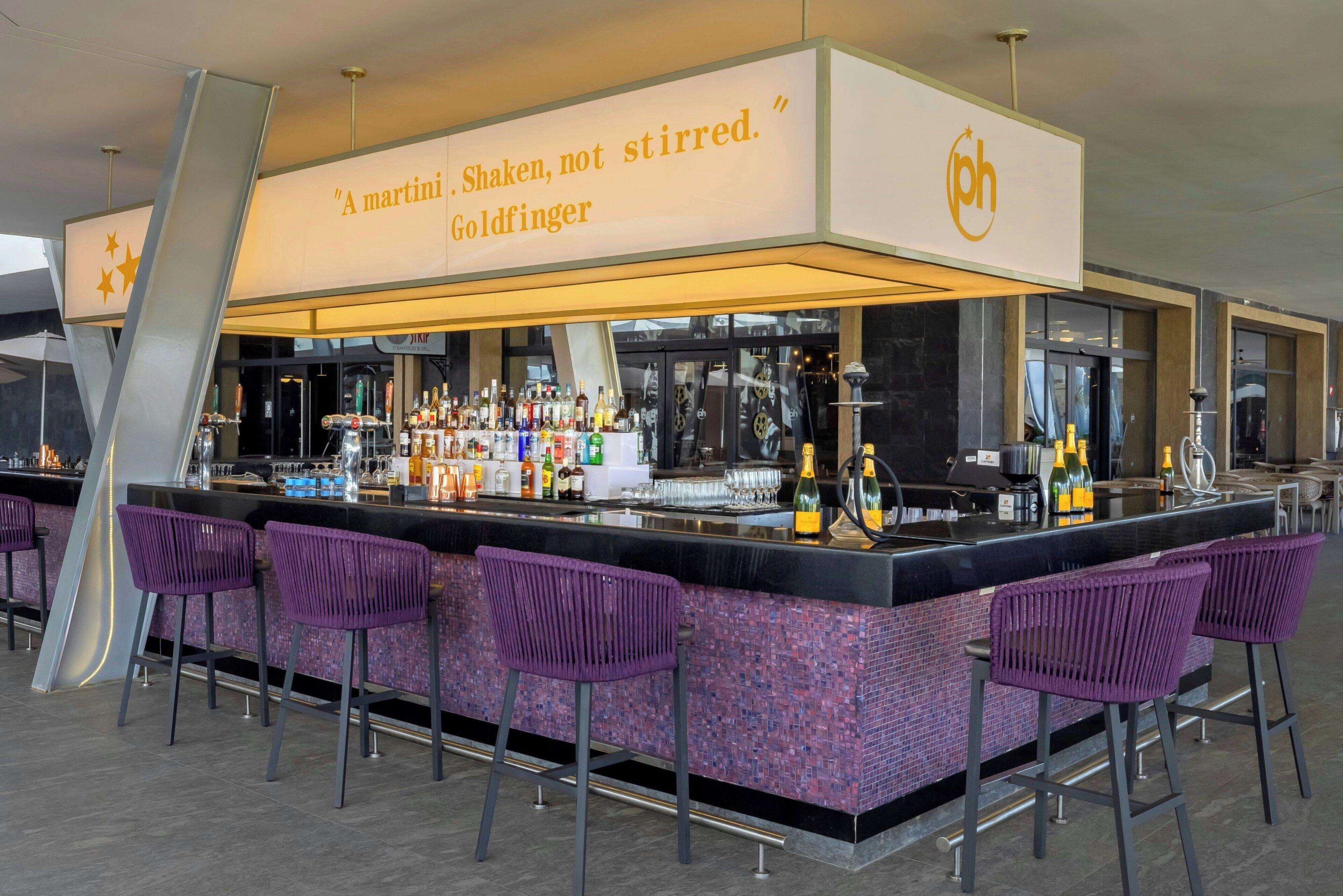 A bar area with a sign reading "A martini. Shaken, not stirred. Goldfinger." and a PH logo.