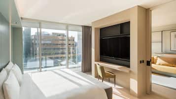 A modern hotel room with a large bed, a desk, a flat-screen TV, and a sofa.