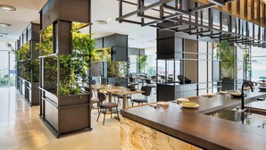 A modern office space with a central island counter, multiple workstations, and vertical gardens.