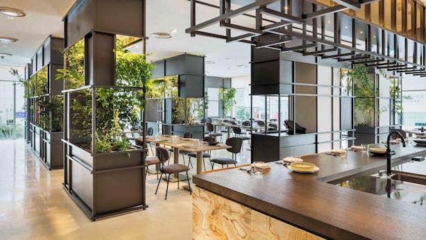 Un espacio de oficina moderno con una isla central, varias estaciones de trabajo y jardines verticales.