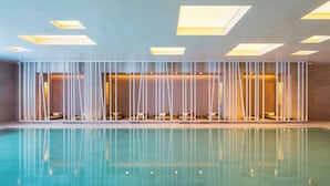 Una piscina con suelo de baldosas y una serie de paneles verticales blancos.
