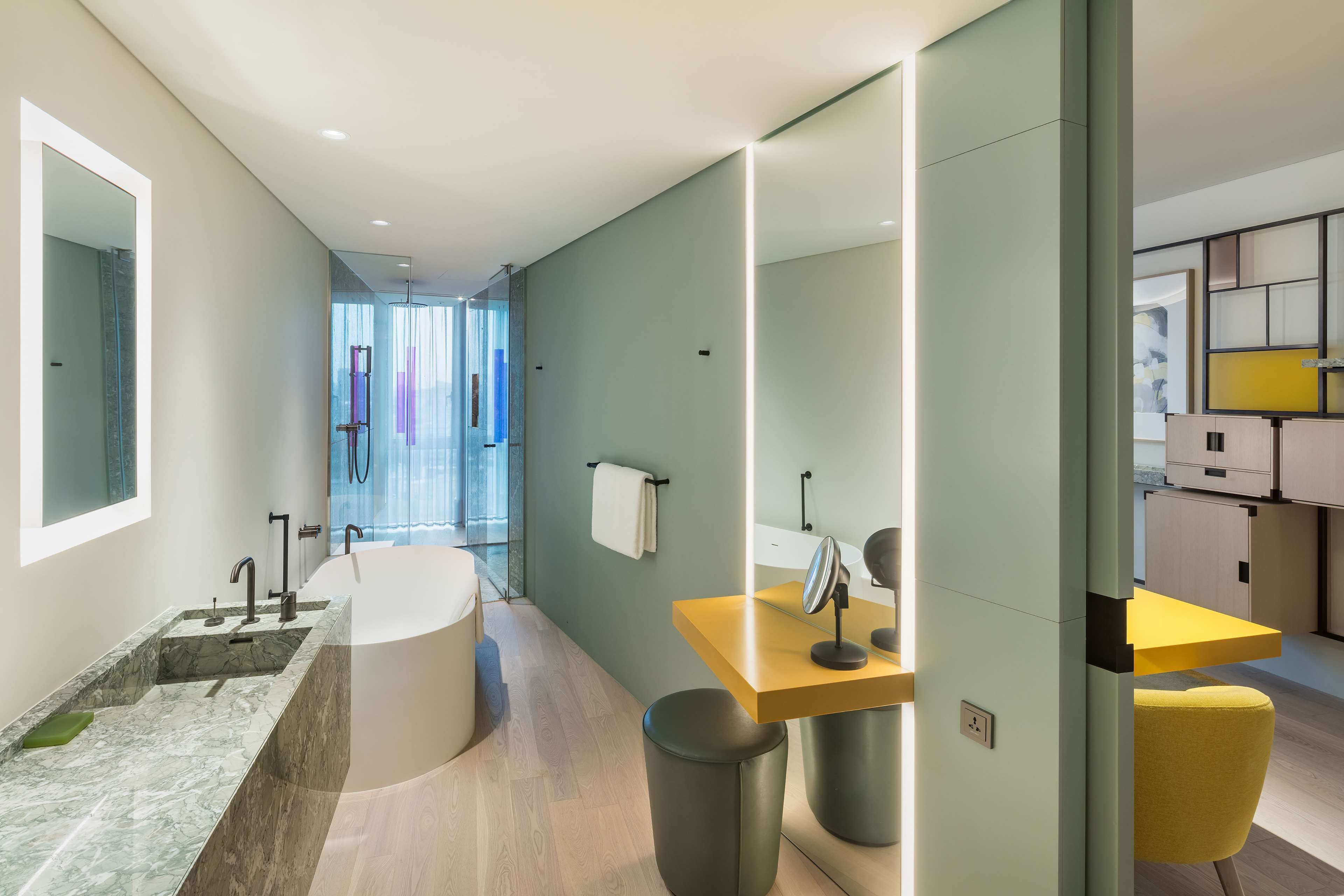A modern bathroom with a marble sink, a freestanding bathtub, and a vanity with a mirror.