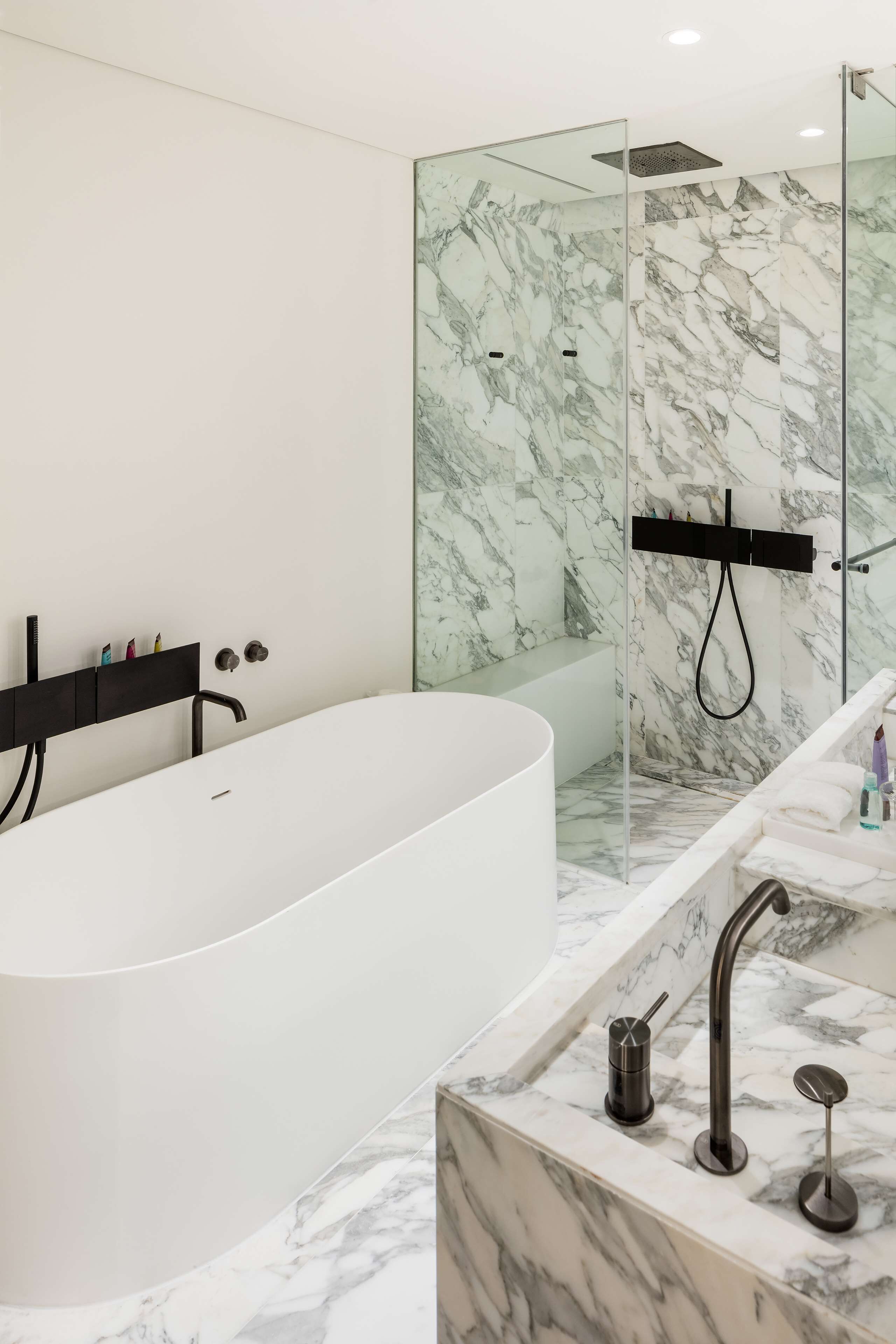 A modern bathroom with a freestanding bathtub, a glass-enclosed shower, and a marble-topped vanity.