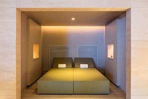 A modern, compact room with a bed, bedside tables, and built-in lighting.