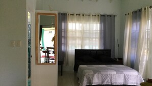 A bedroom with a bed, a ceiling fan, and a window with curtains. - Best Villas Tobago (Lowlands)