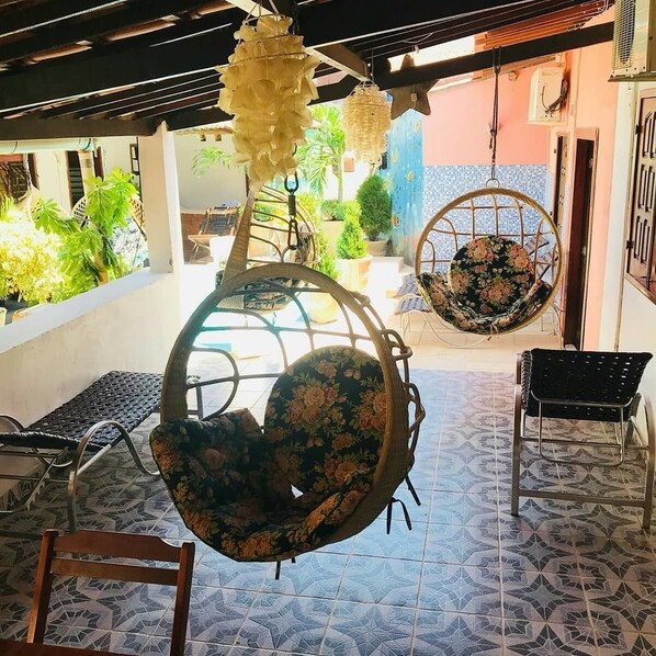 A covered outdoor seating area with hanging chairs and a patterned floor.