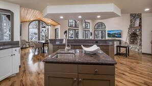 A spacious kitchen with a granite countertop, wooden cabinets, and a stone fireplace. - Paradise Awaits - Updated Donner Lake Home, Private Hot Tub, Dog Friendly, BBQ and Big Deck (Truckee)