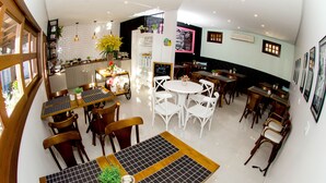 Un restaurante con varias áreas de comedor, incluyendo una mesa redonda central con sillas blancas y una mesa rectangular más pequeña con manteles individuales negros.