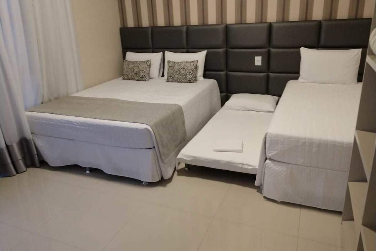 Una habitación de hotel con una cama grande, otra más pequeña y una cama sofá.