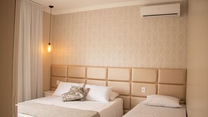 Habitación de hotel con dos camas, un papel tapiz estampado, aire acondicionado y una lámpara de noche.