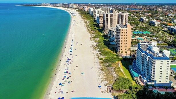 Un paysage urbain côtier avec une vaste plage, de hauts immeubles et un ciel bleu dégagé.