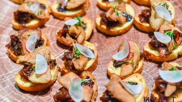 A tray of appetizers with various toppings, including meat and vegetables, arranged on a table.