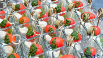 A tray of appetizers with skewers, including red and white spherical items and green garnishes.