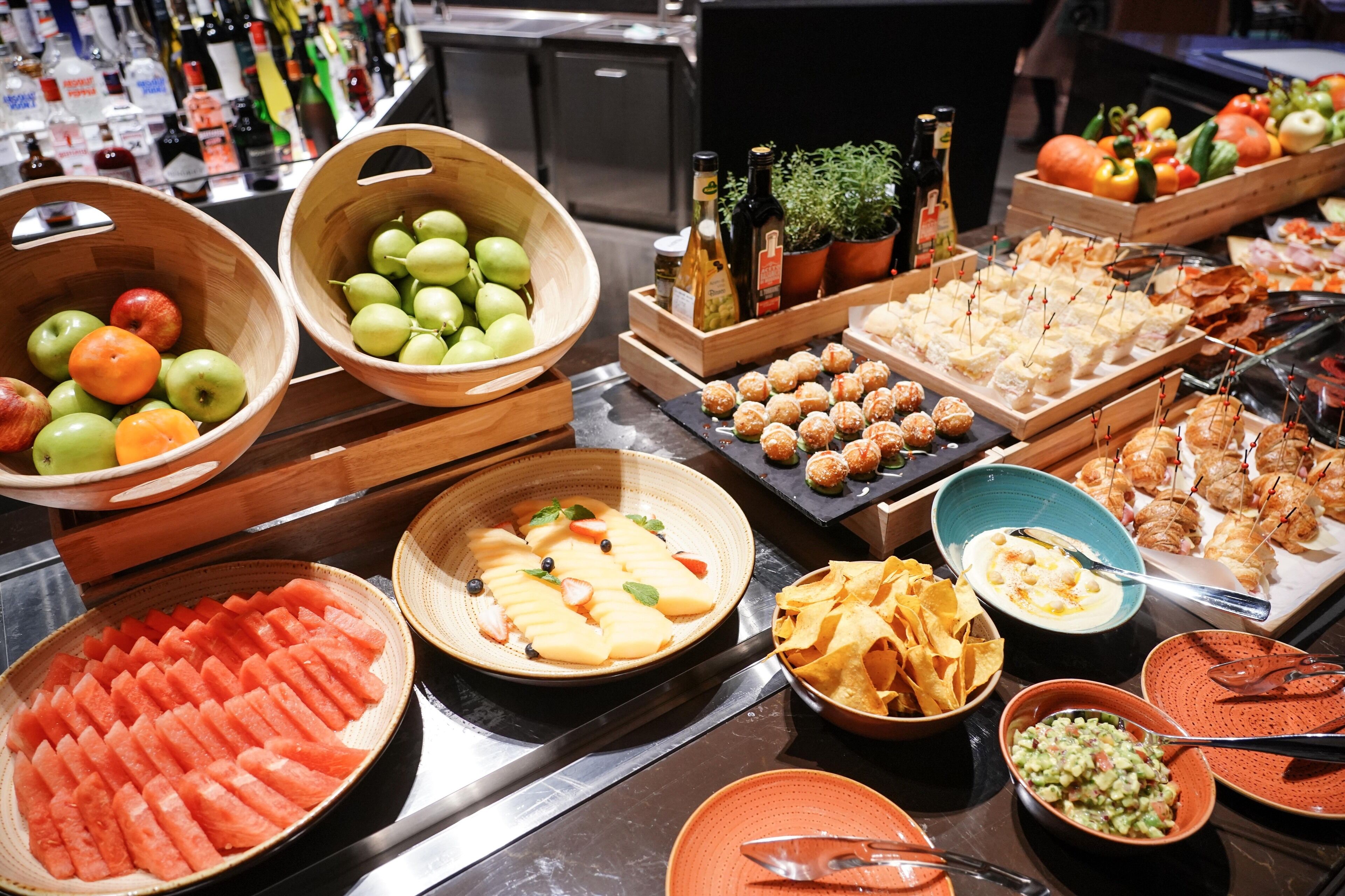 Un bufé con diversas opciones de comida, como frutas, verduras y aperitivos.