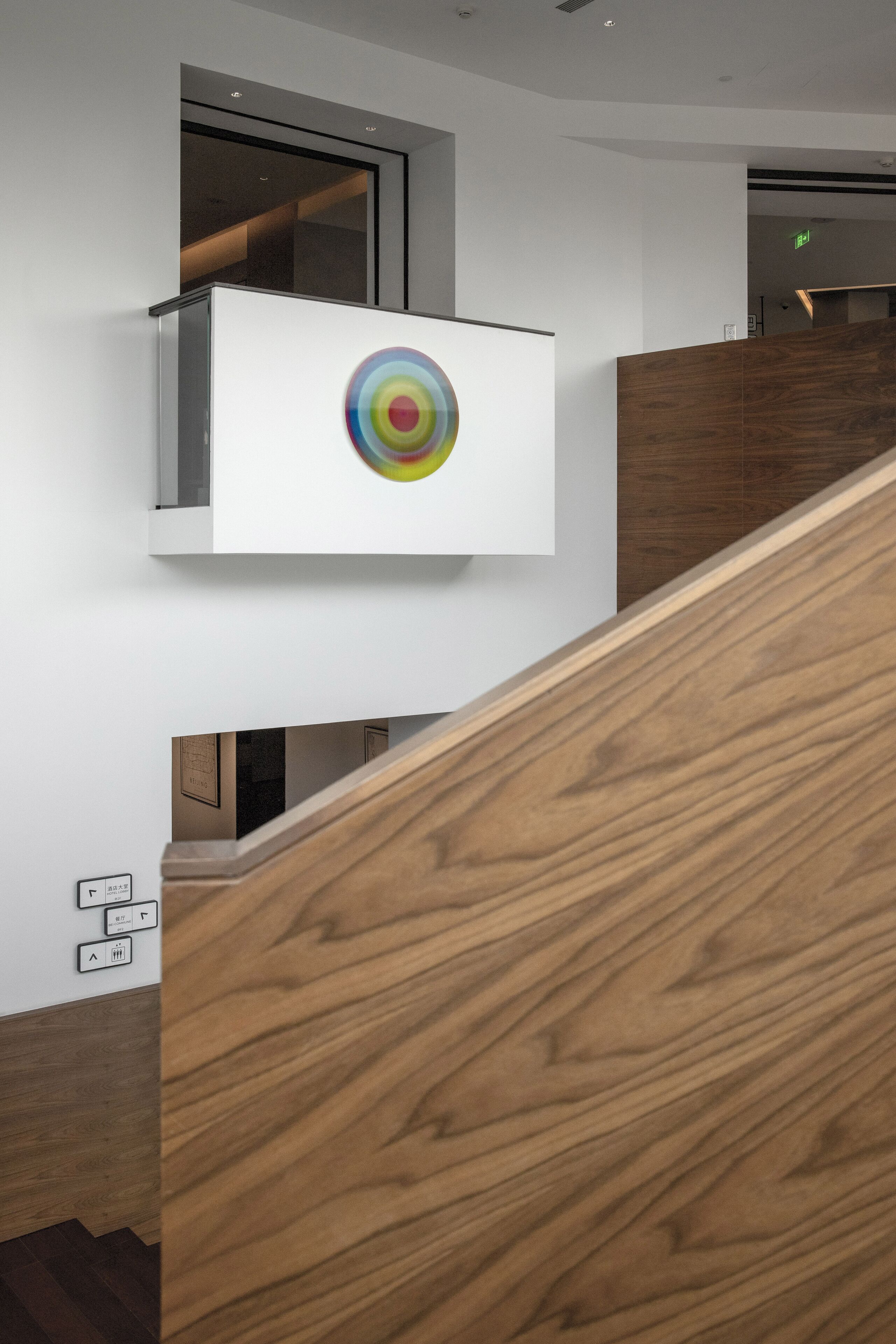 Un interno moderno con una scala in legno, un'opera d'arte bianca a parete e una porta in vetro.