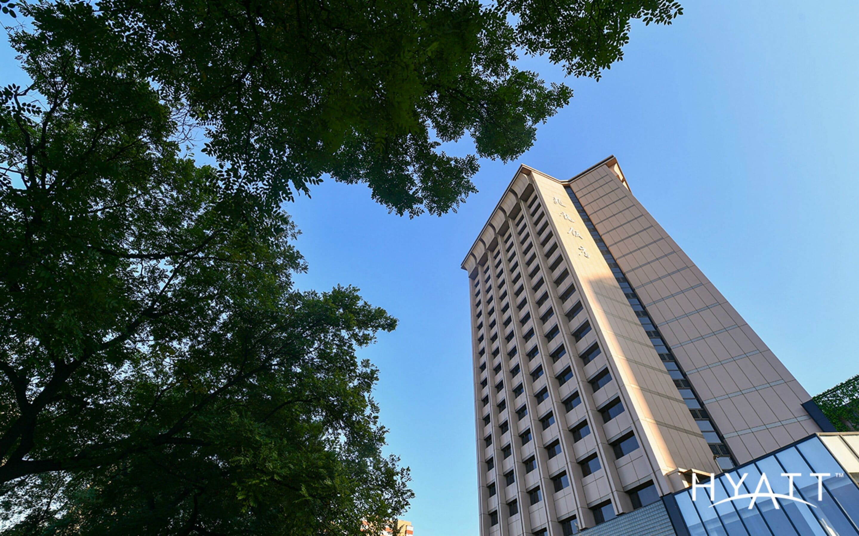 A tall building with a modern design, featuring a prominent logo at the base.