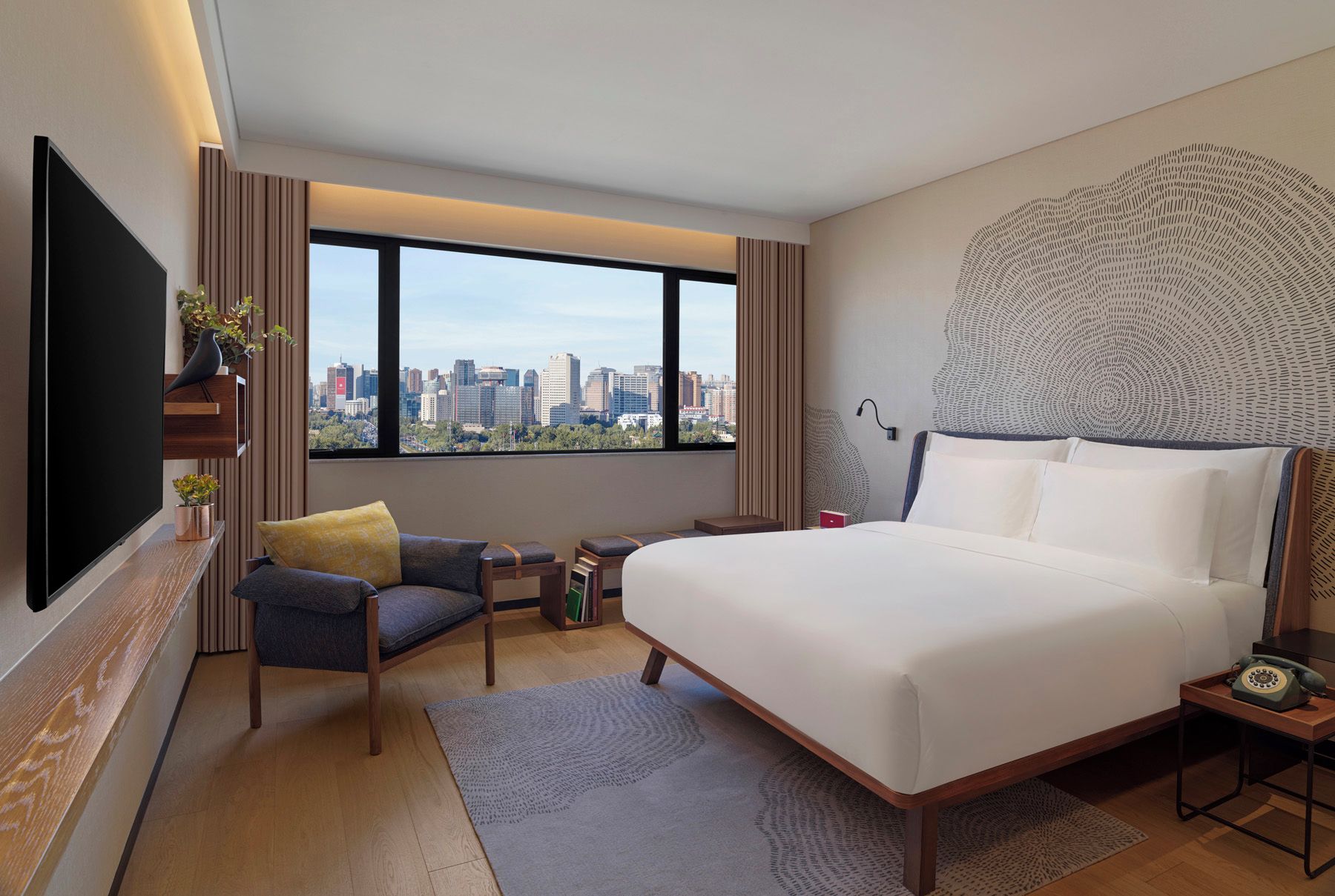 Une chambre d’hôtel moderne avec un grand lit, un canapé, une télévision et une vue sur la ville.