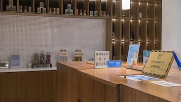 A reception desk with a "World of Hyatt" sign, a "Check in" sign, and a "Reception" sign. There are jars labeled "Infused Water" and "Syrup & Powder".