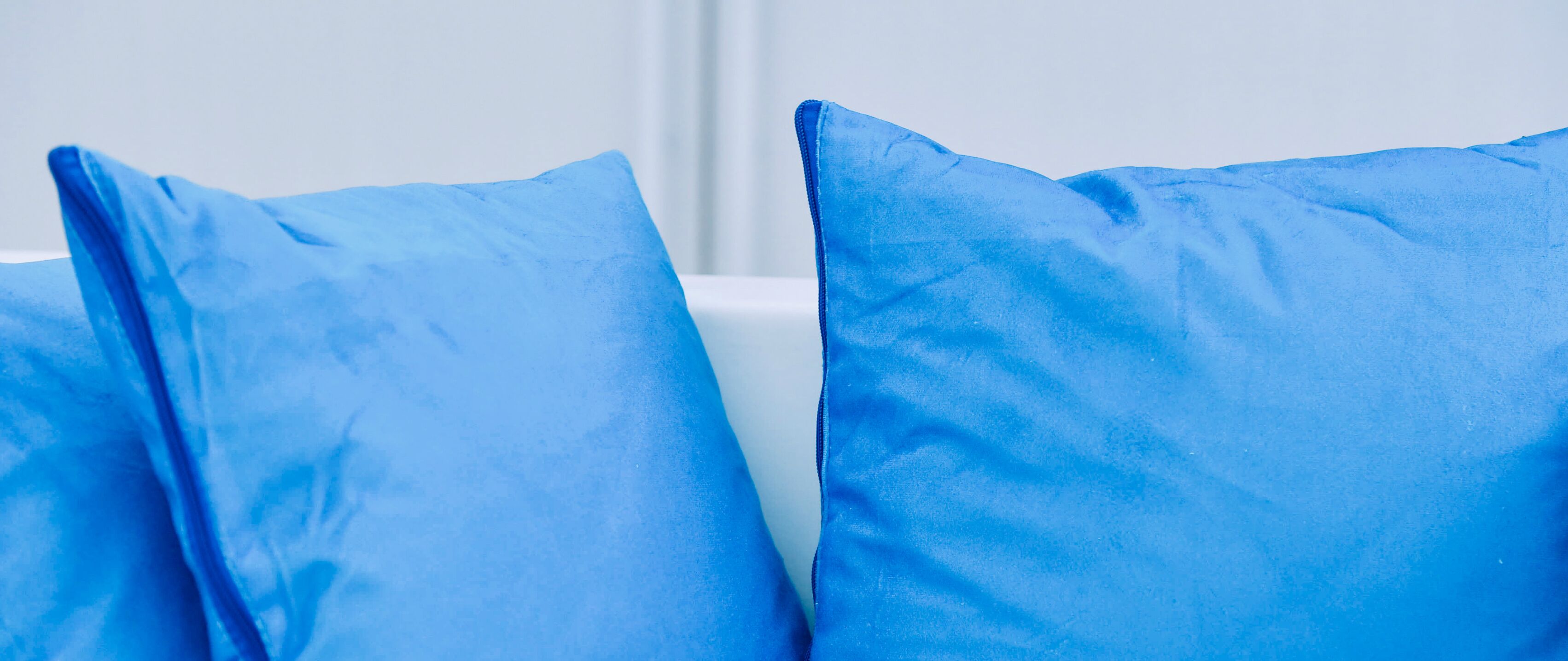 Primer plano de dos almohadas azules sobre fondo blanco.