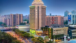 A high-rise building with a prominent triangular roof, surrounded by other residential and commercial buildings. - BEI Zhaolong Hotel, part of JdV by Hyatt (Beijing)