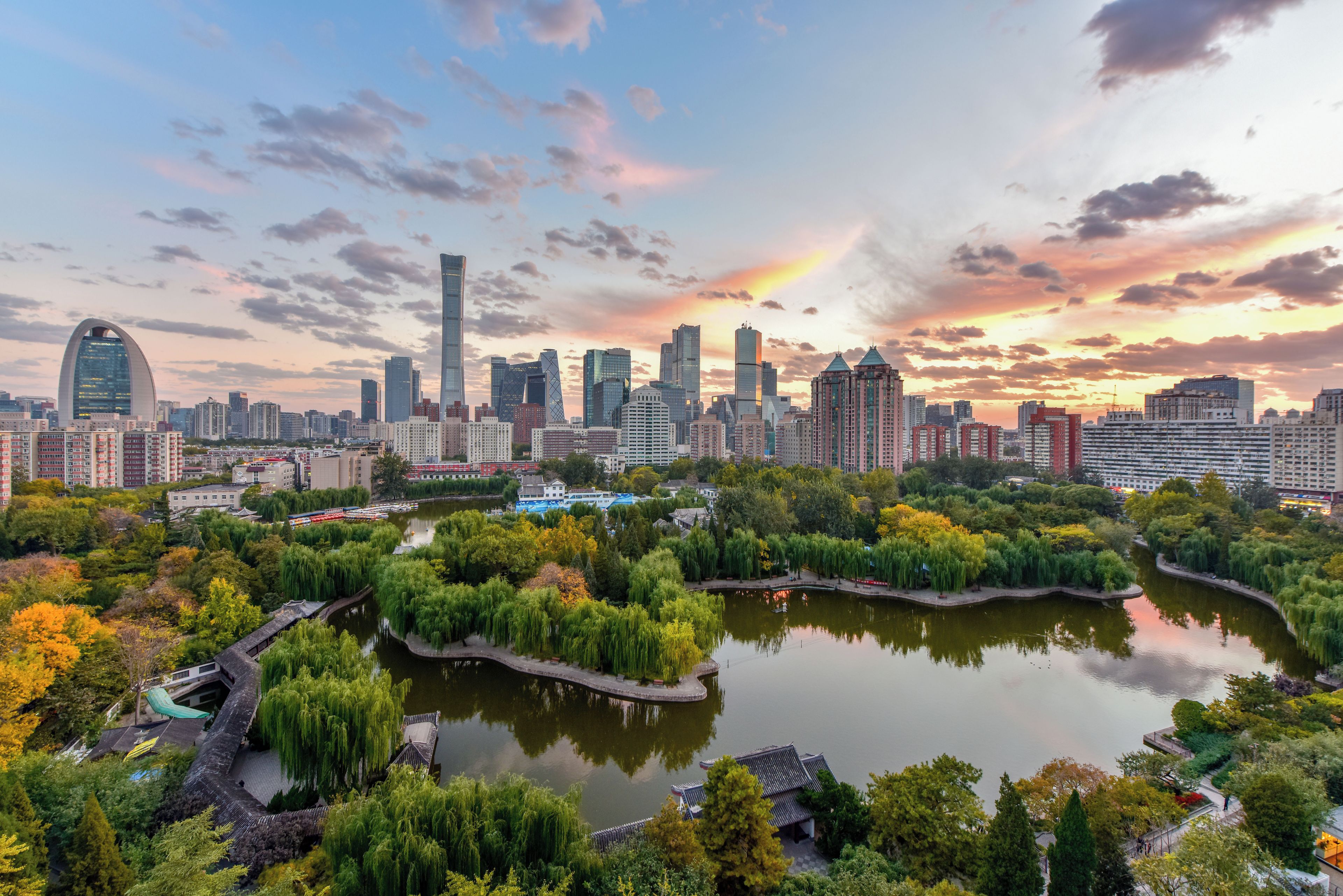 A cityscape with a river, trees, and traditional architecture.