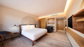 A modern hotel room with a large bed, a desk, a chair, and a TV mounted on the wall.