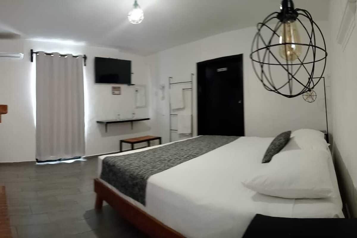 A bedroom with a bed, a small table, a TV, and a door.
