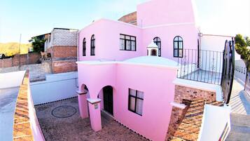 Un bâtiment rose doté d’une cour, d’un mur en pierre et d’une clôture en métal.