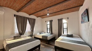 Una habitación con tres camas, techo de ladrillo y suelo estampado.