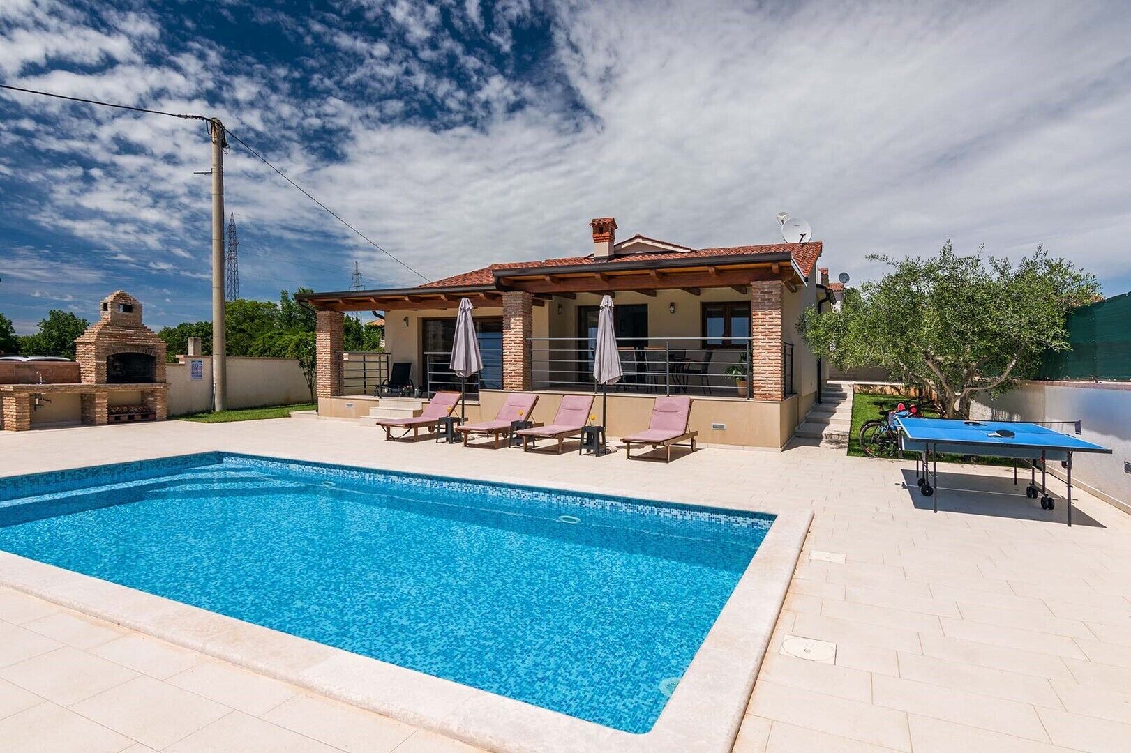 A house with a swimming pool, a barbecue area, and a table tennis table.