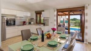 Una cocina moderna con electrodomésticos integrados y un comedor con vista a una piscina.