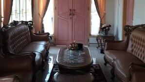 A room with a wooden ceiling, a pink door, and a table with a vase of flowers.