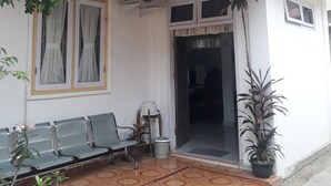 A building with a covered entrance, a bench outside, and potted plants.