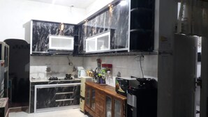 A kitchen with black marble cabinets, a wooden cabinet, a stove, and a refrigerator.