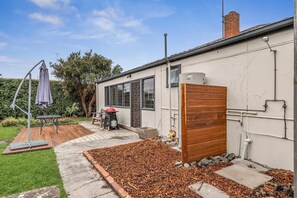 A residential property with a patio, a wooden fence, a water tank, and a garden area.