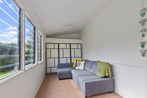 A room with a grey sofa, a green throw blanket, and a white wall with a black and white panel design.