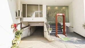 A hotel entrance with a staircase leading to a second floor, a glass door, and a small indoor garden area. -  Hotel Smart by Kelvish Hotel (New Delhi)
