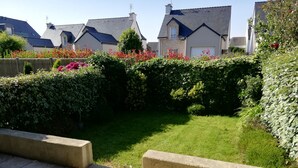 A residential garden with a well-maintained lawn, stone borders, and a variety of flowering plants. - Studio with garden at the doors of the beach and thalasso ROSCOFF (Roscoff)