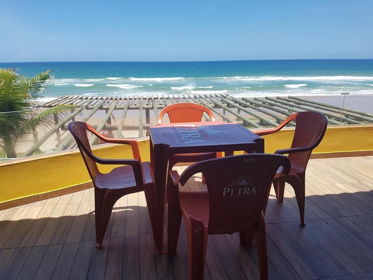 Una terraza de madera con una mesa y cuatro sillas, con vistas al océano.