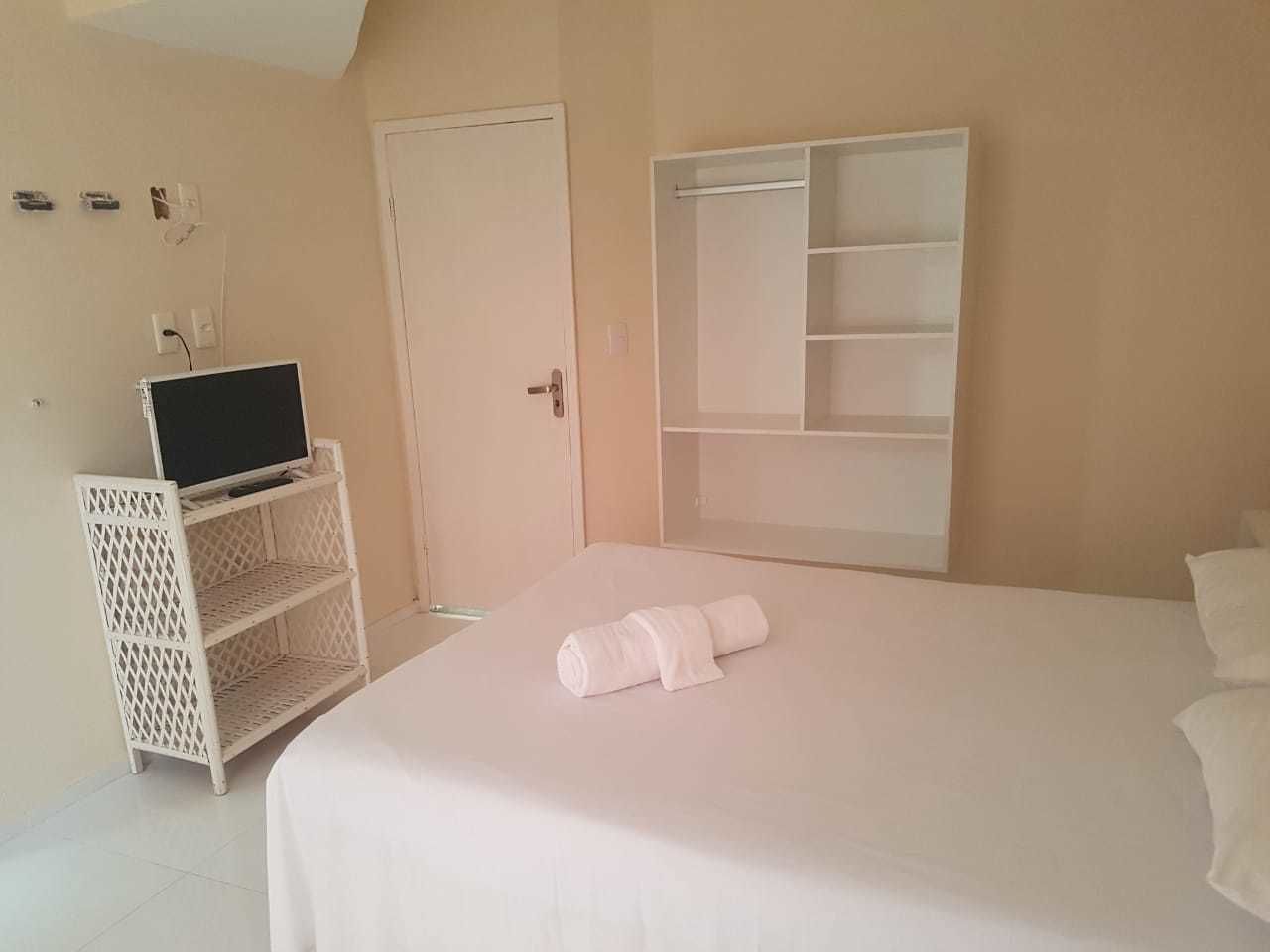 Ein Schlafzimmer mit einem Bett, einem Fernseher auf einem Schrank und einem Kleiderschrank.