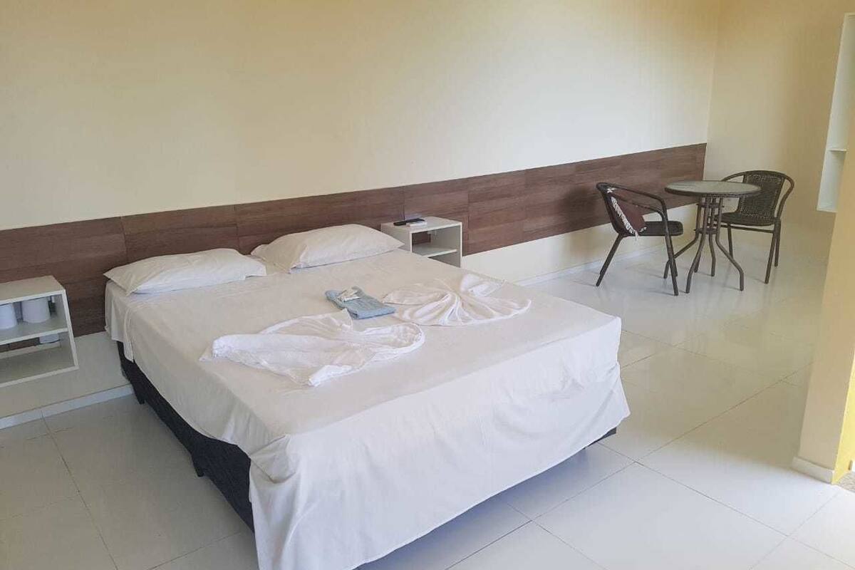 A hotel room with a large bed, two bedside tables, a chair, and a small table.