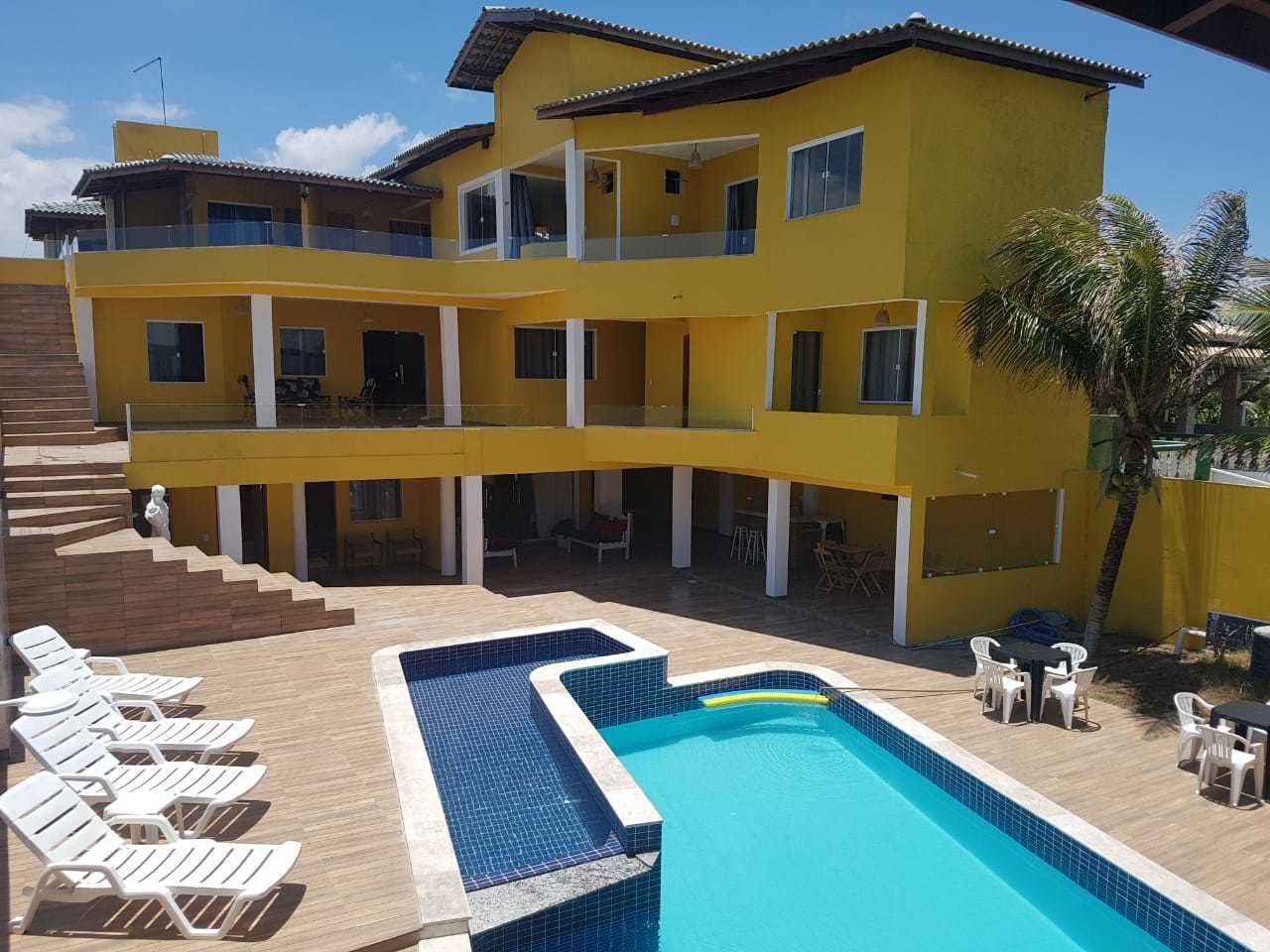 Un bâtiment jaune à deux étages, doté d’une piscine, d’un espace extérieur aménagé et d’un escalier menant à l’étage supérieur.