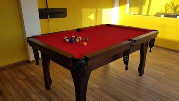 A pool table with balls in a room with wooden flooring and yellow walls.