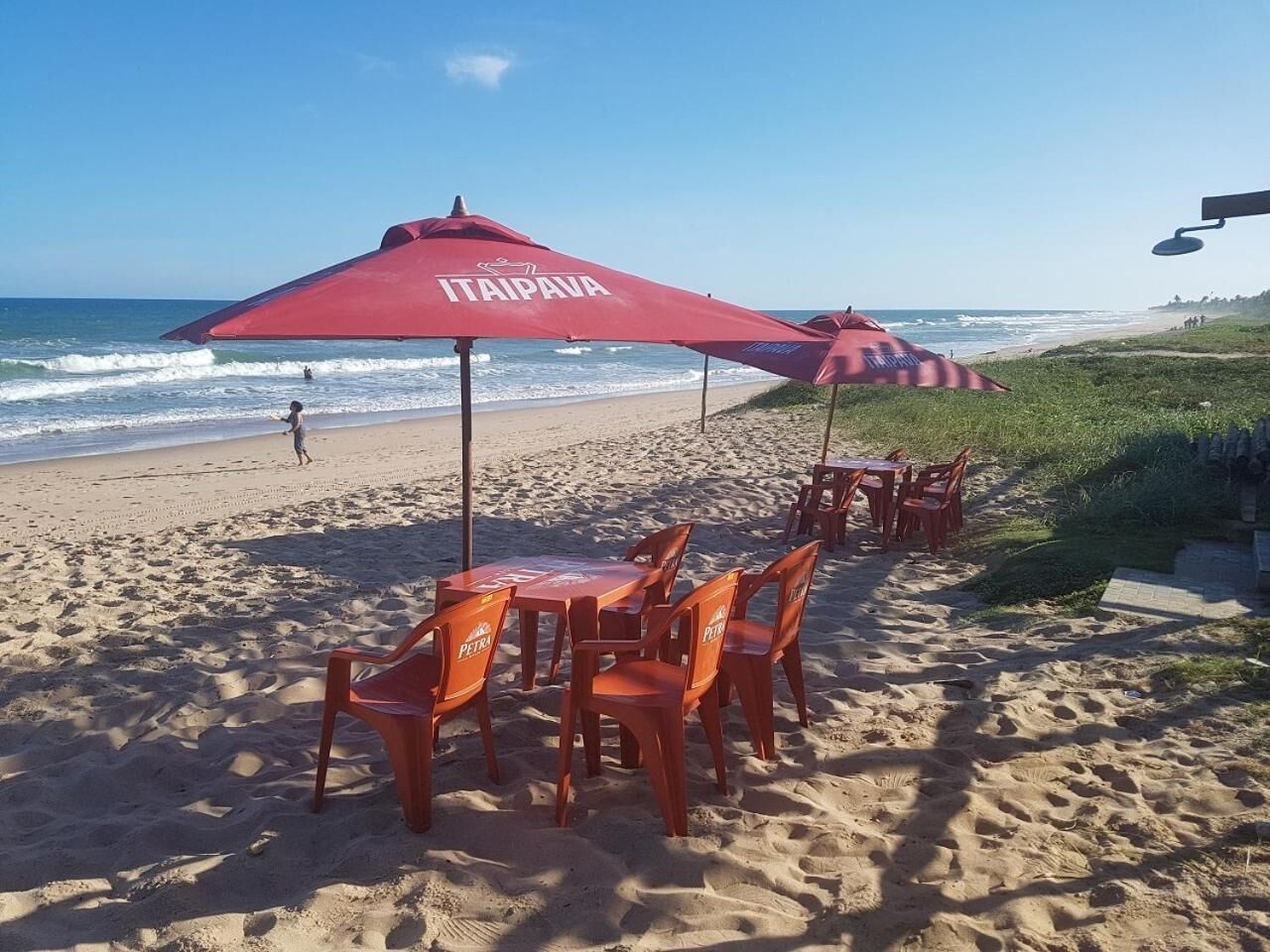 A beachside seating area with red umbrellas and chairs labeled "PETRA".