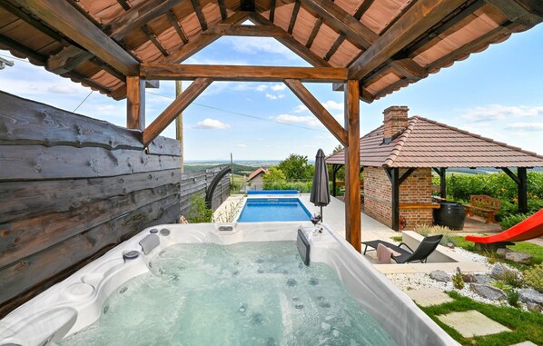 Relax in a serene hot tub surrounded by a pergola and lush greenery, with a sauna or bar nearby.
